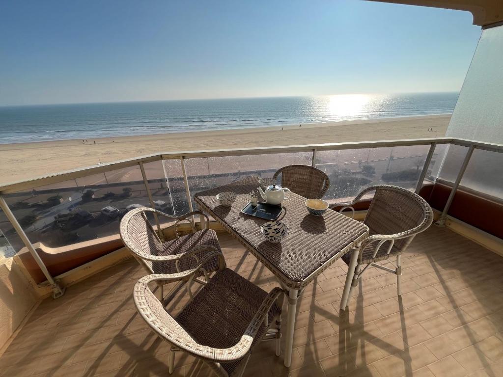 une table et des chaises sur un balcon avec la plage dans l'établissement Evasion marine, à Plage-des-Demoiselles