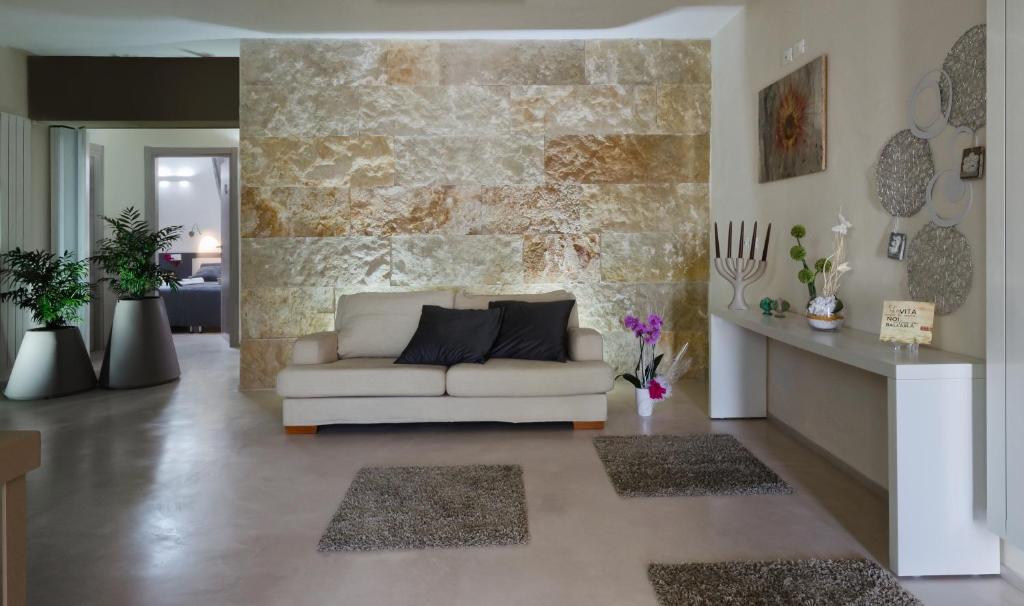ein Wohnzimmer mit einem weißen Sofa und einer Steinmauer in der Unterkunft B&B Radici in Melendugno