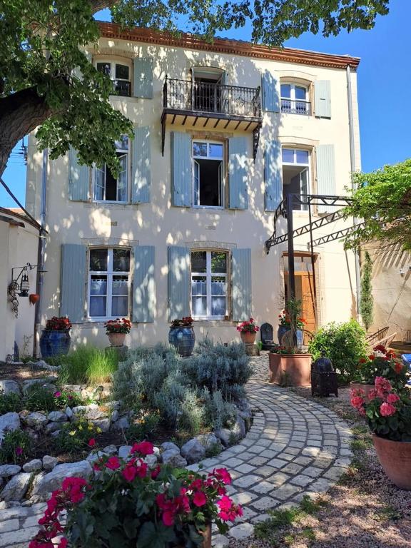 une maison blanche avec des fleurs devant elle dans l'établissement Les gites du tilleul, à Villefranche-de-Lauragais