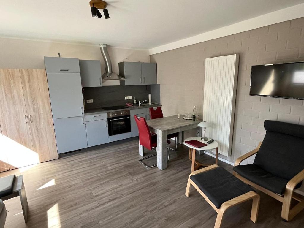 a living room with a table and a kitchen at Hempen Fied Gästehaus - Apartment 3 in Bad Zwischenahn