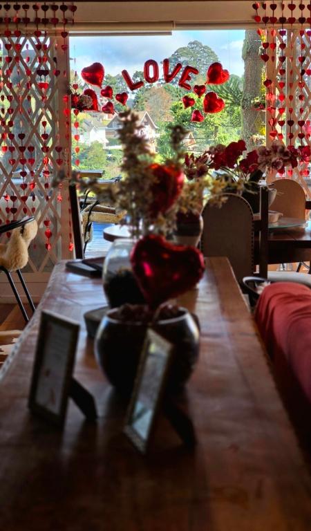 a table with flowers and a window with the word love at Recanto dos Moinhos - Boutique Hotel in Campos do Jordão