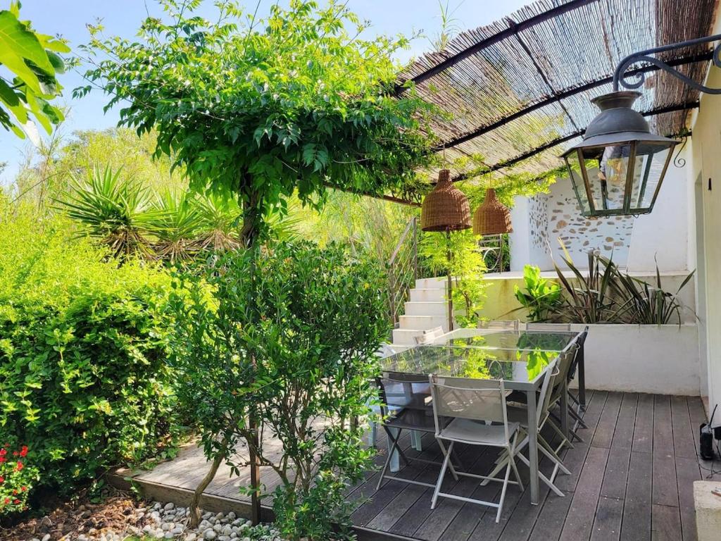 une terrasse avec une table et quelques buissons et arbres dans l'établissement Charmante maison de hameau, à La Londe-les-Maures