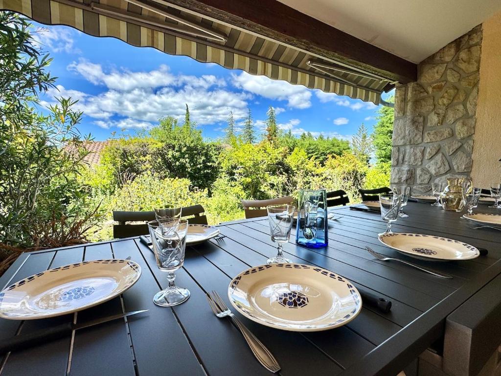 une table en bois avec des assiettes et des verres à vin dessus dans l'établissement Grande maison au cœur de l'Ardèche 12 personnes, à Villeuneuve-de-Berg