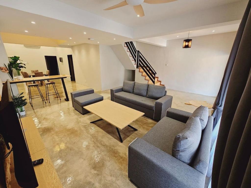 a living room with couches and a table and stairs at Gold Plus Homestay 5970 in Kuantan