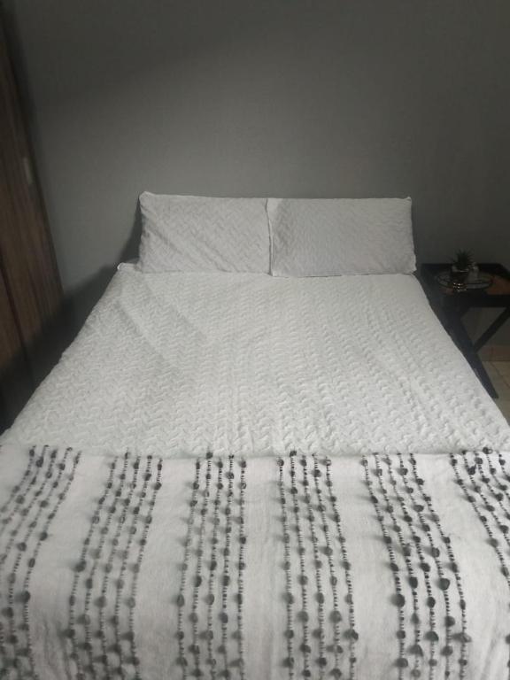 a white bed with a black and white blanket on it at Melee's house in Richards Bay