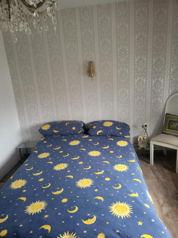 a bed with a blue comforter with yellow sun patterns at Ambergers exklusive Ferienwohnungen in Maar