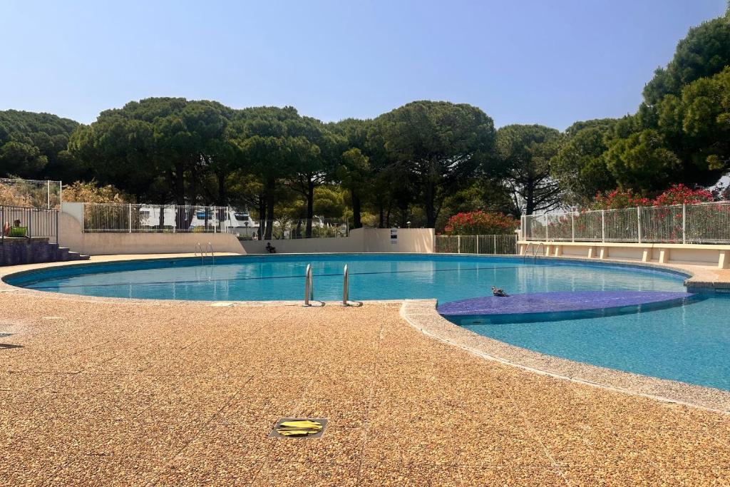 une grande piscine au milieu d'un parc dans l'établissement Le Quai aux Fleurs - Résidence avec piscine proche de la mer, au Grau-du-Roi