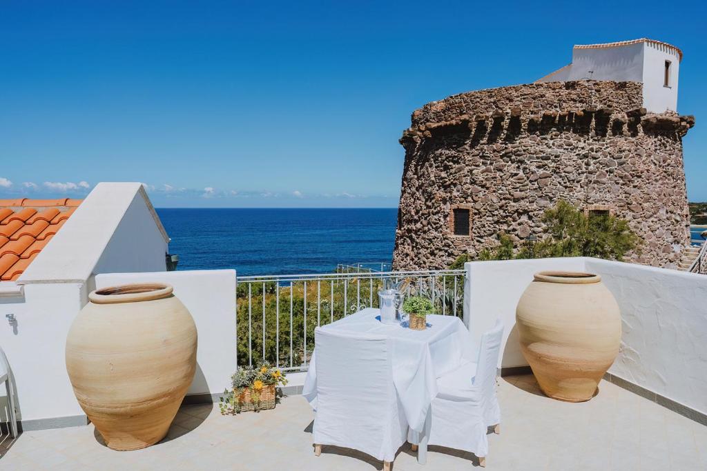 a table and two large vases on a balcony with the ocean at Vento d'Estate B&B in Portoscuso