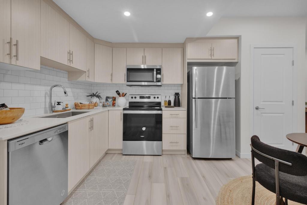 a kitchen with white cabinets and a stainless steel refrigerator at 1 BR Suite Stylish Coffee Station Stocked sleep 4 in Edmonton