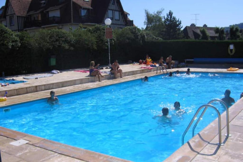 un groupe de personnes nageant dans une piscine dans l'établissement Charmant studio rénové cosy, à Deauville