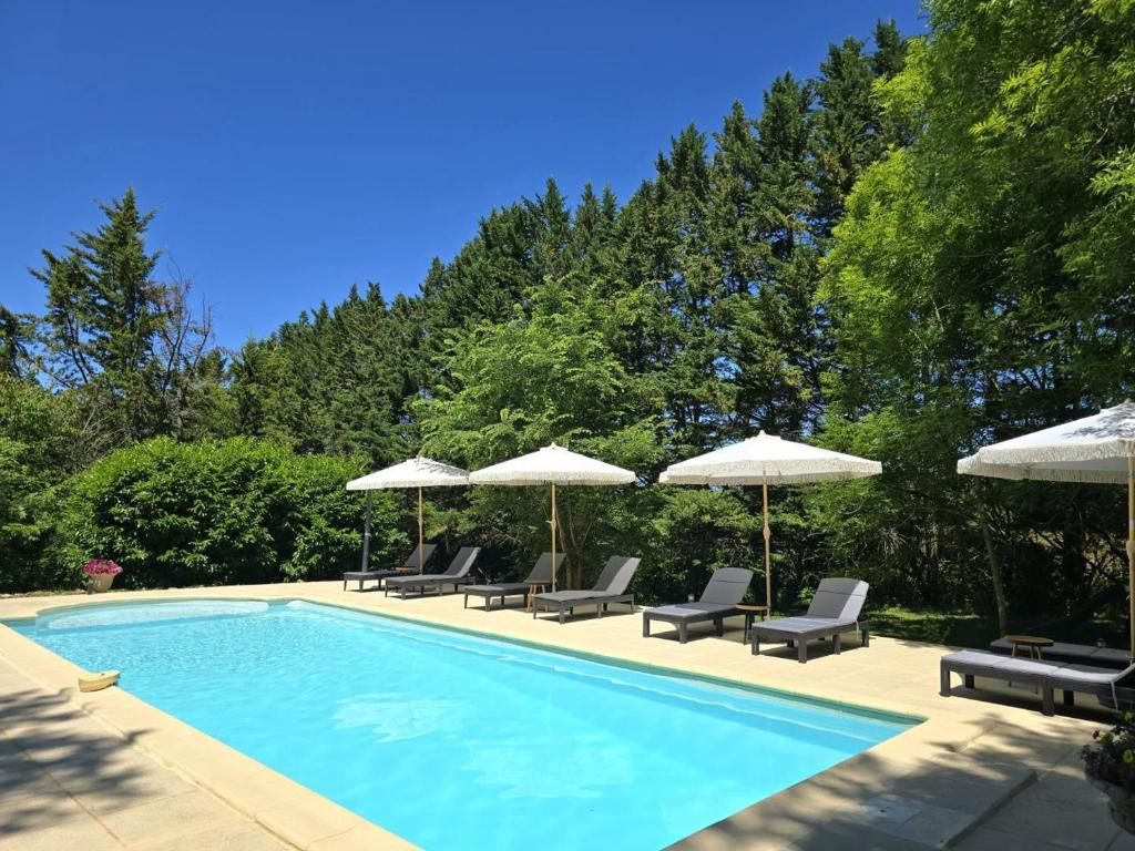 a swimming pool with chairs and umbrellas at Gîte de charme en Dordogne avec piscine et jardin - FR-1-616-485 in Berbiguières