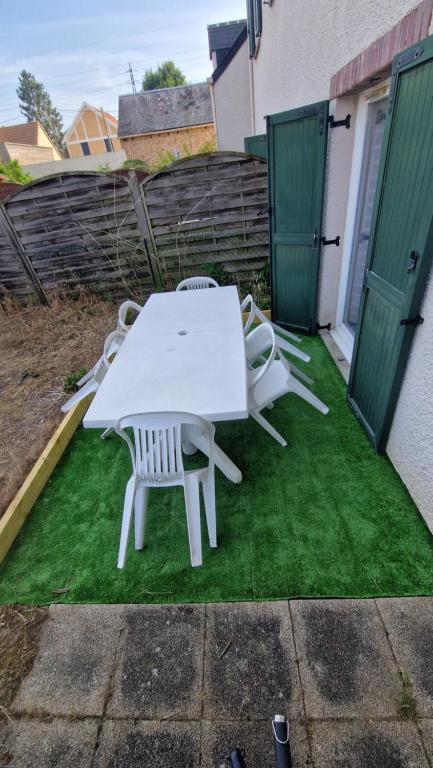 une table et des chaises blanches assises sur l'herbe dans l'établissement Maison 2 chambres à 5 mn du circuit des 24 heures du Mans proche toute commodités, à Arnage