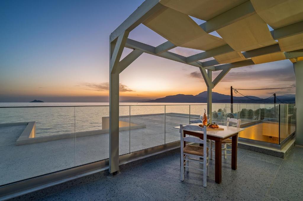 a table and chairs on a balcony with a view of the ocean at Pelagos Home in Kalamaki Heraklion