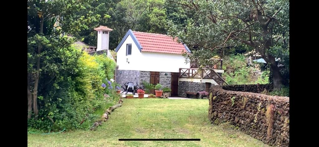 une maison blanche avec un toit rouge dans une cour dans l'établissement Mountain View Cottage, à Seixal