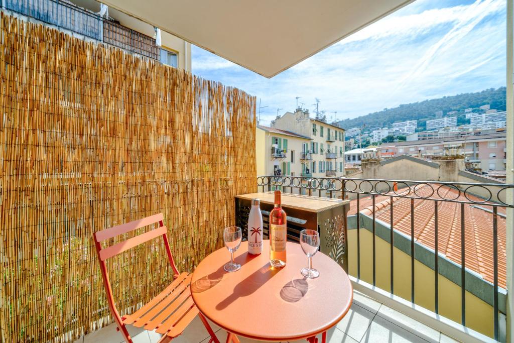 une table avec deux verres à vin sur un balcon dans l'établissement Studio port de Nice Clim Balcon, à Nice