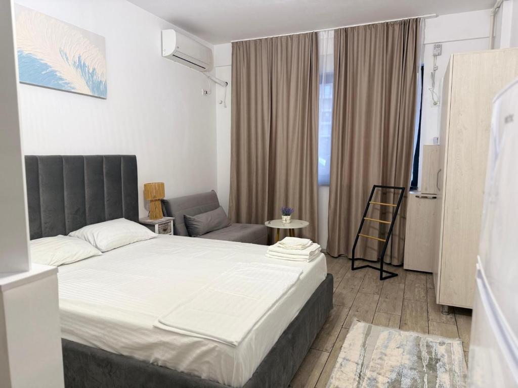a bedroom with a large bed and a chair at Luxury beach studio in Mamaia Nord