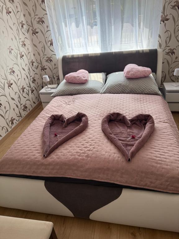 a bed with two heart shaped towels on it at Dió Apartman in Hajdúszoboszló