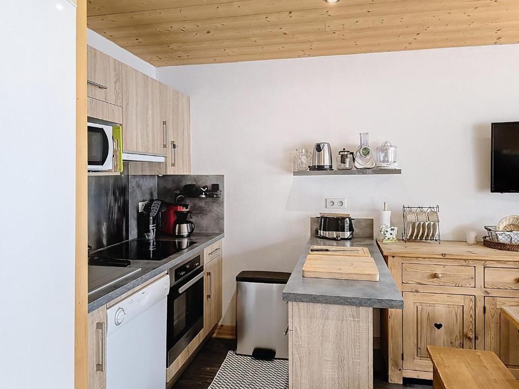une cuisine avec des armoires en bois et un comptoir dans l'établissement Appartement rénové 2 chambres, balcon sud, à 50m des pistes et commerces - La Toussuire - FR-1-416-145, à La Toussuire