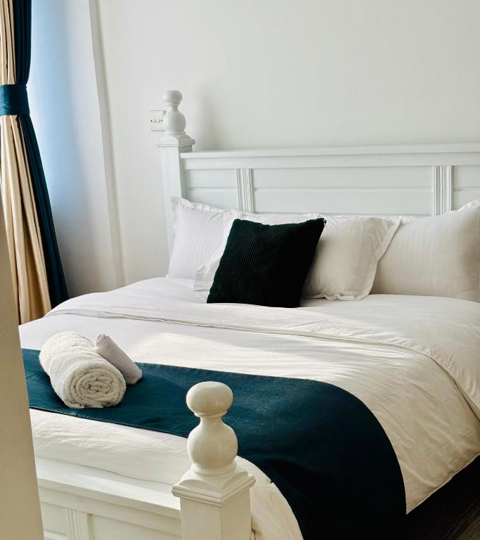 a white bed with black and white pillows on it at Lina Apartment in Nairobi