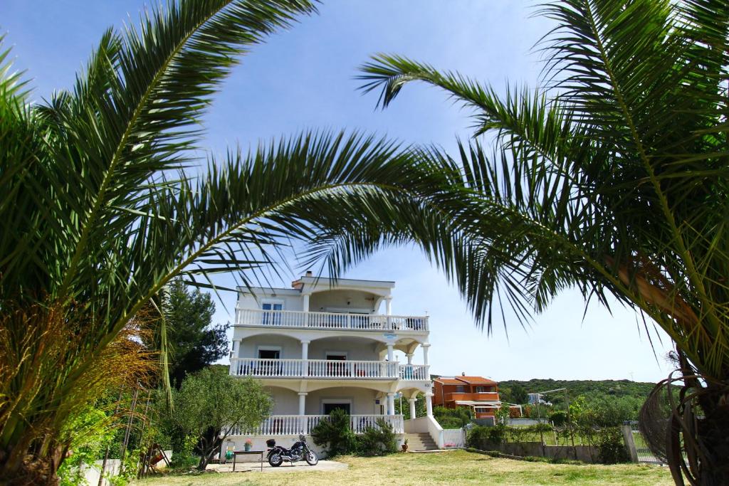 una gran casa blanca con palmeras delante en Apartments Natali, en Sveti Petar