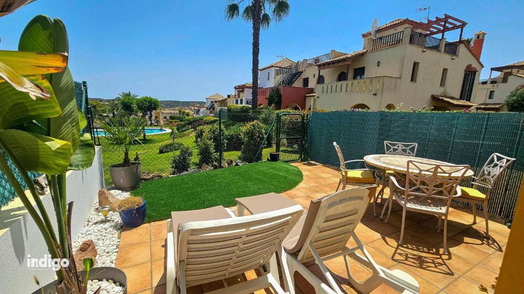 een patio met een tafel en stoelen en een tuin bij ANN001 Bright Two Bedroom Townhouse in Ayamonte