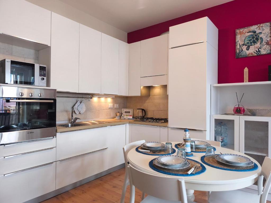 a kitchen with white cabinets and a table with plates on it at Casa al Mare WiFi Ac in Chioggia