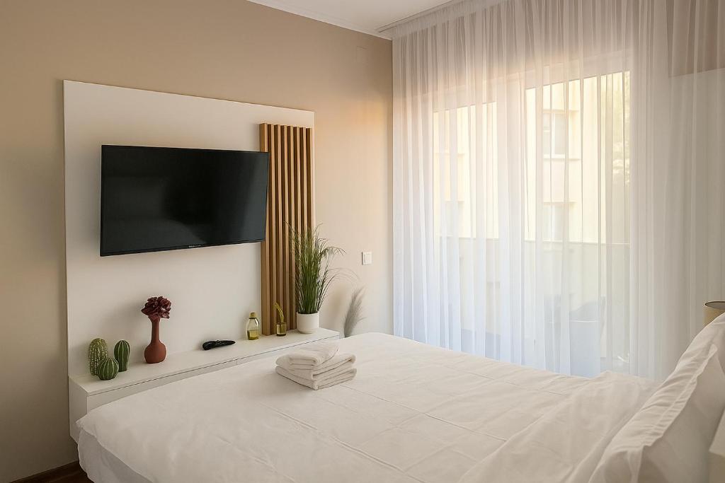 a bedroom with a white bed with a flat screen tv at Arena 7-17 Central Suites in Cluj-Napoca