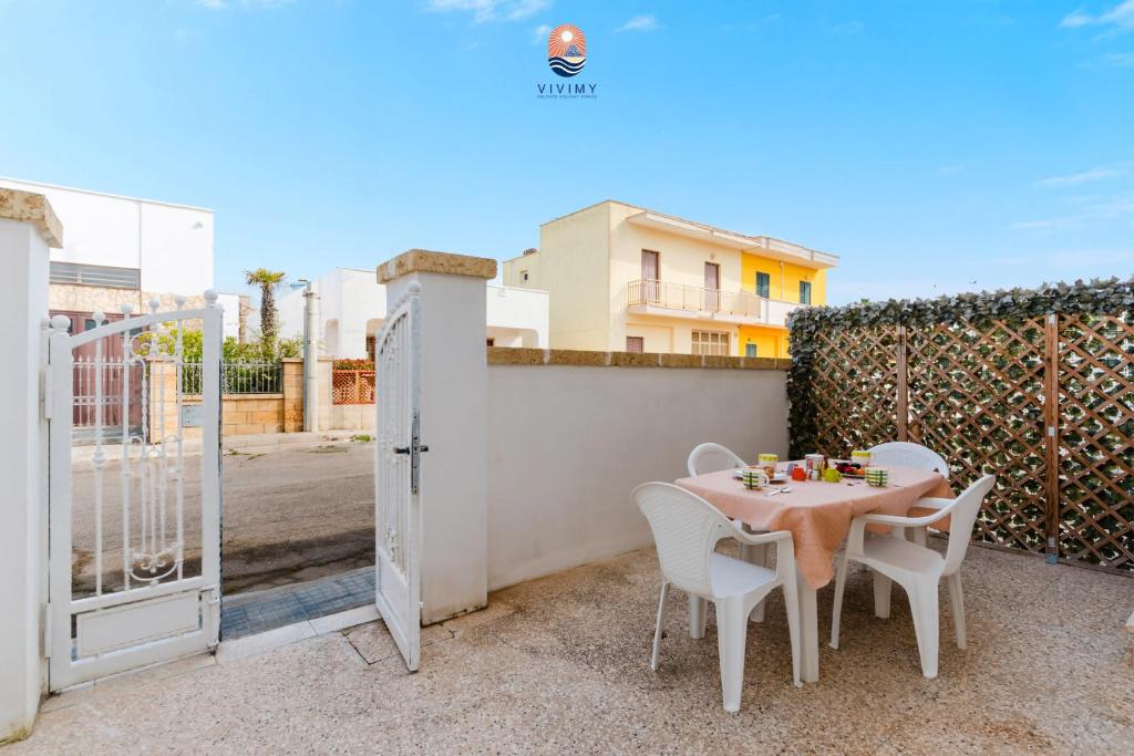 eine Terrasse mit Tisch und Stühlen und einem Zaun in der Unterkunft Dimora Lucy by Vivimy in Taviano