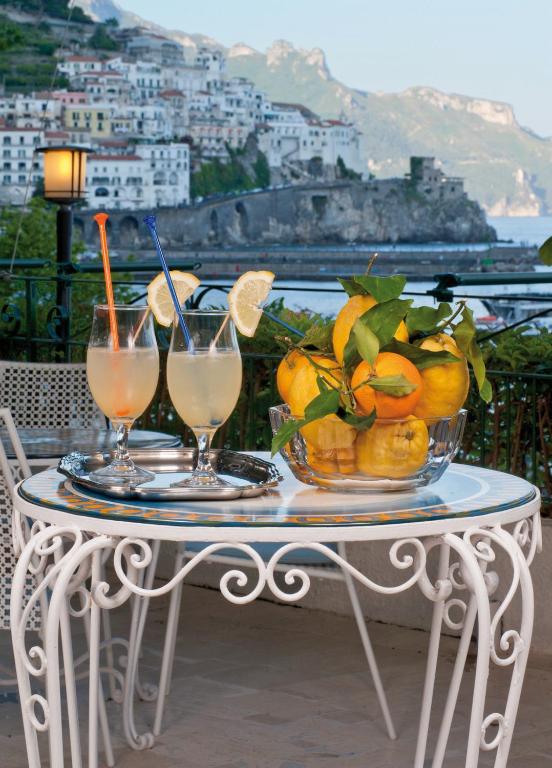 a table with a bowl of fruit and two glasses of juice at Hotel Aurora in Amalfi