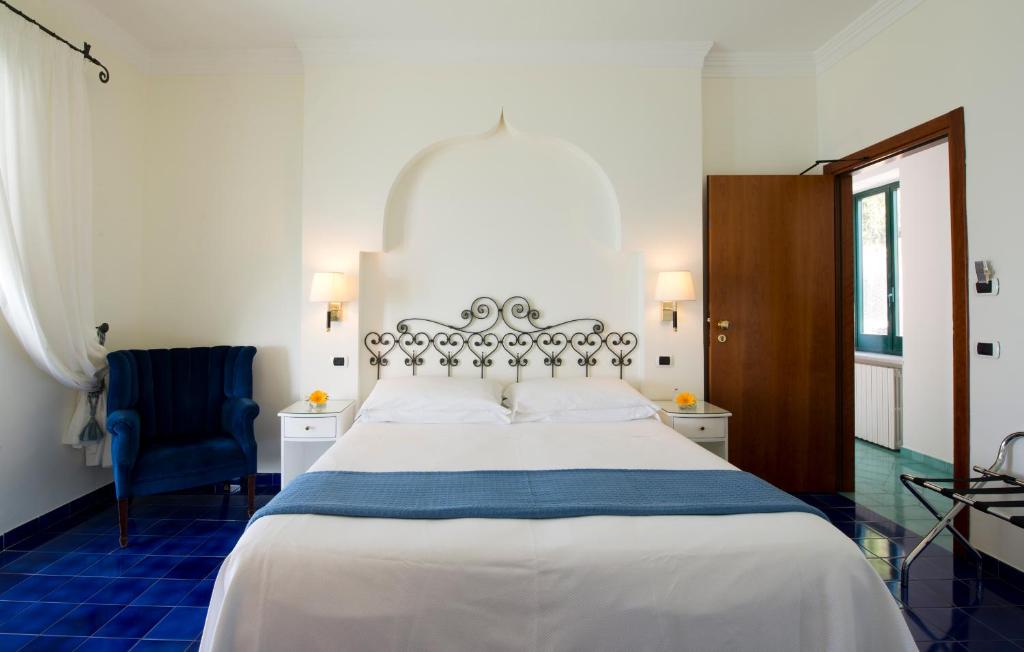 a bedroom with a large white bed and a chair at Hotel Aurora in Amalfi