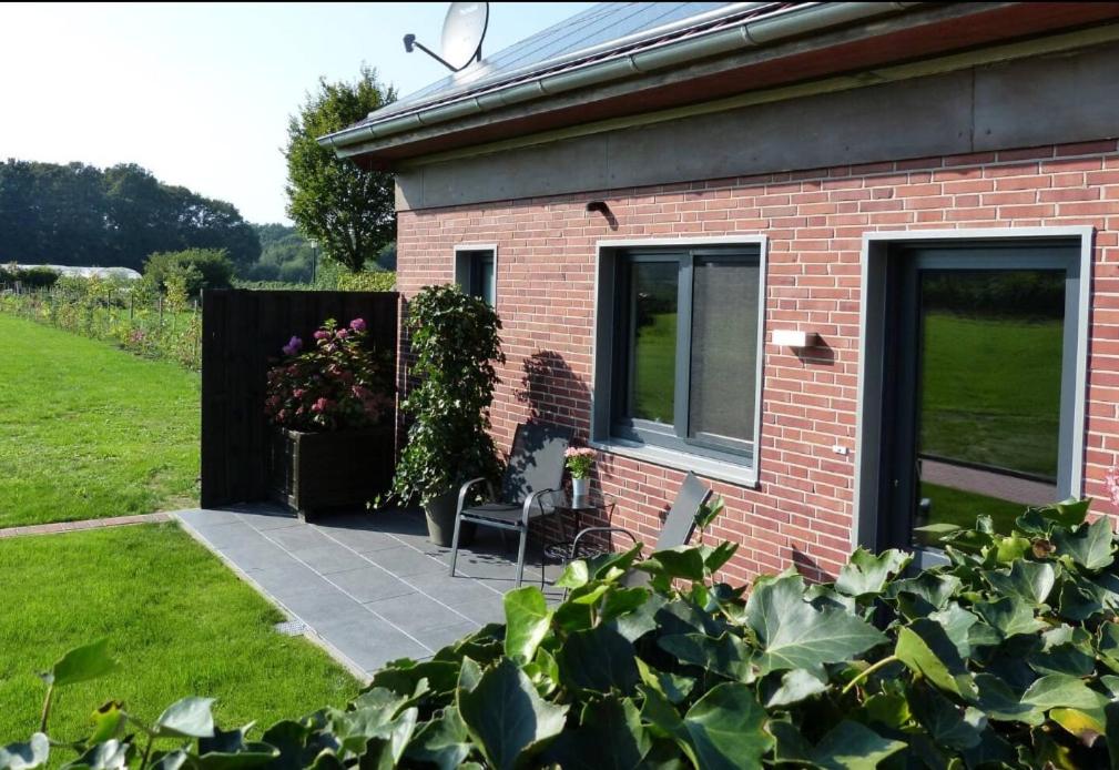 a brick house with a patio with a chair at Hempen Fied Gästehaus - Apartment 4 in Bad Zwischenahn