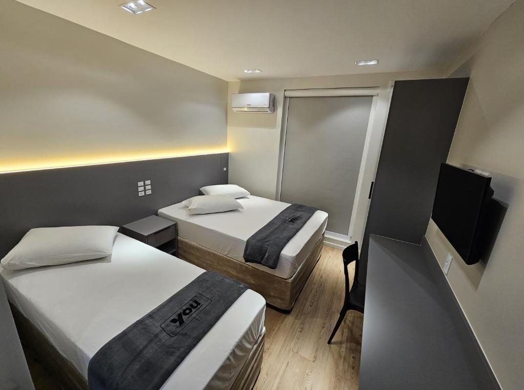 a small room with two beds and a television at You Hotéis Inteligentes Tubarão in Tubarão