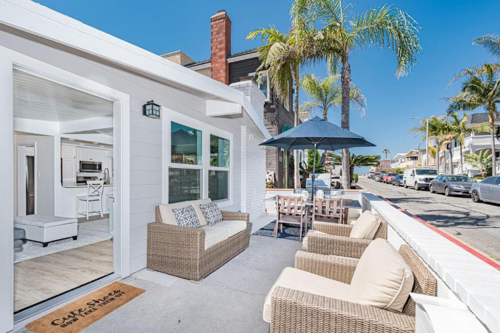 a patio with wicker chairs and an umbrella at Renovated 2Br W Oceanview Patio Steps From 40Th St Beach By Beachview Rentals in Newport Beach