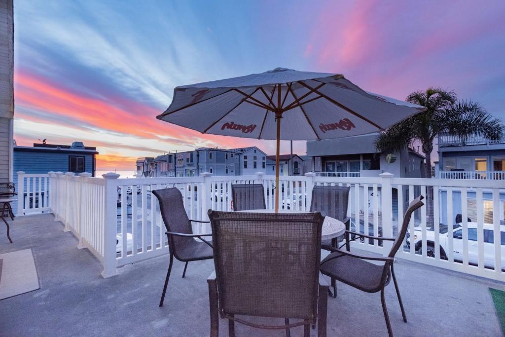 a table and chairs with an umbrella on a balcony at Spacious 4Br W Oceanview Balcony & Bbq Steps To Sand By Beachview Rentals in Newport Beach