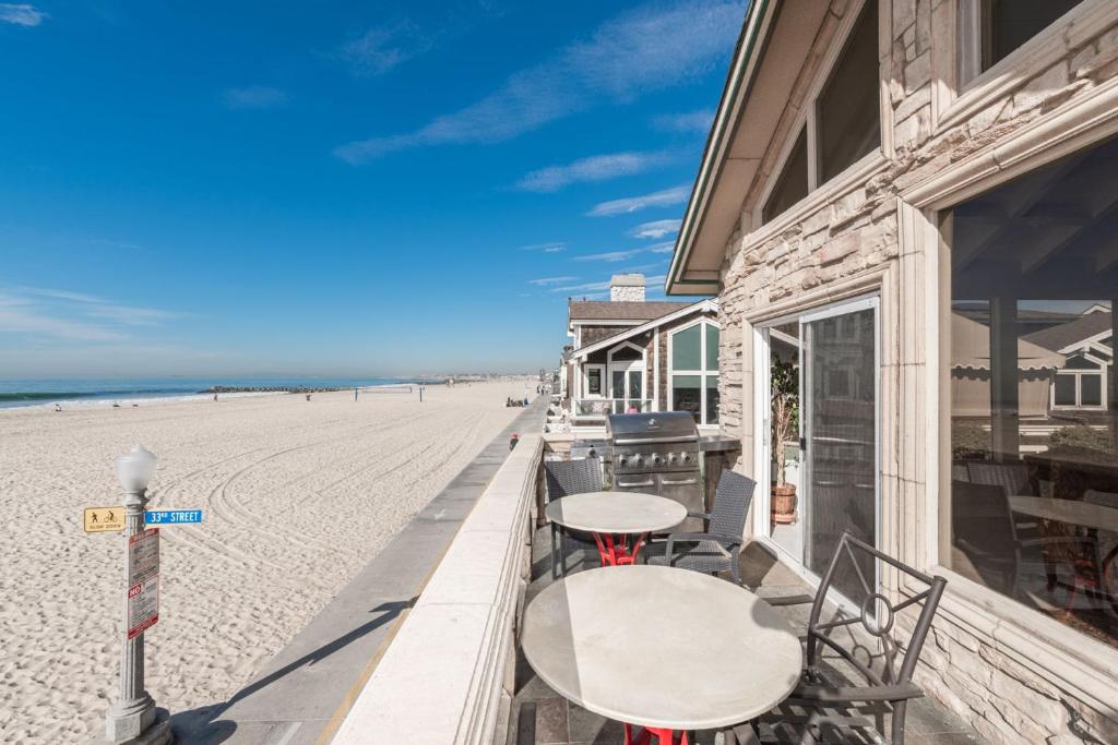 a table and chairs on the beach next to a building at 7Br Beachfront Retreatstunning Ocean Views & Walkable Fun By Beachview Rentals in Newport Beach