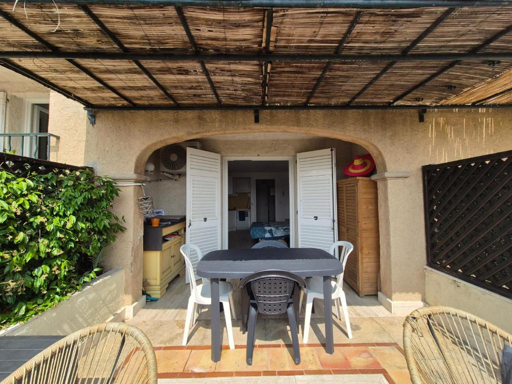 un patio avec une table et des chaises sous une pergola dans l'établissement Charmant Mazet à 250m de la Plage San Peire aux Issambres, à Saint-Peïre-sur-Mer