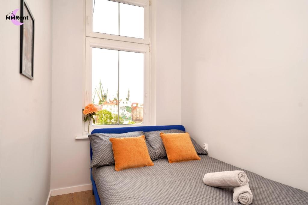 - un lit avec des oreillers orange dans une chambre avec une fenêtre dans l'établissement MMRent Umbrella Room, à Gdańsk