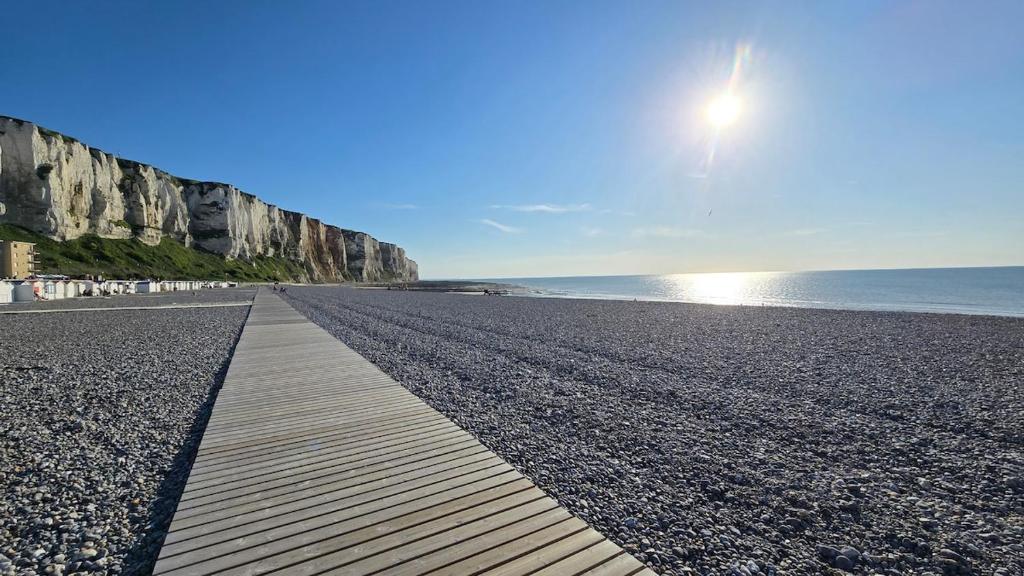 a boardwalk on a beach with the ocean and cliffs at Le treport - centre - Plain-pied 1 chambre in Le Tréport