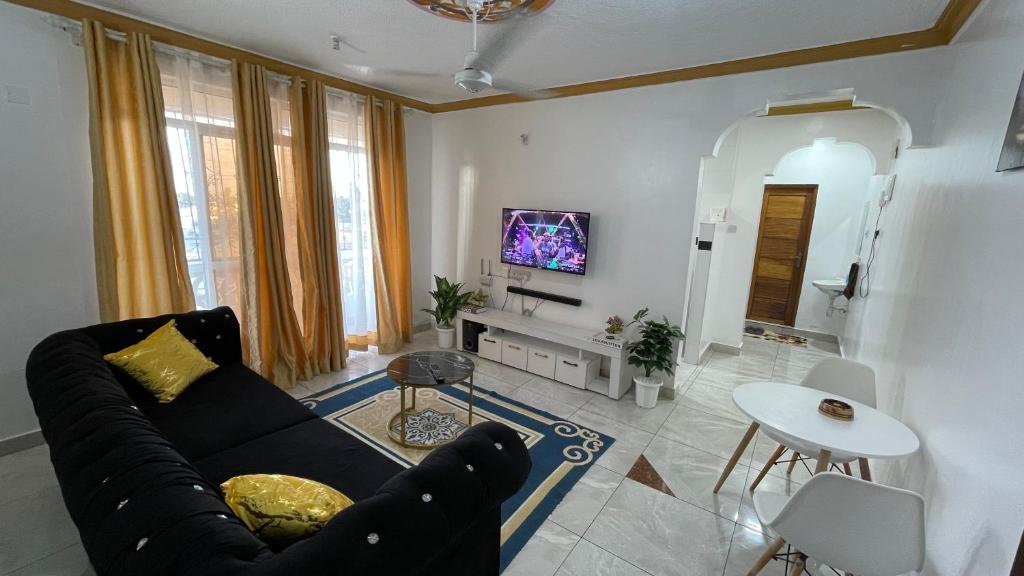 a living room with a black couch and a tv at DRE'S WORLD STAYs in Mombasa