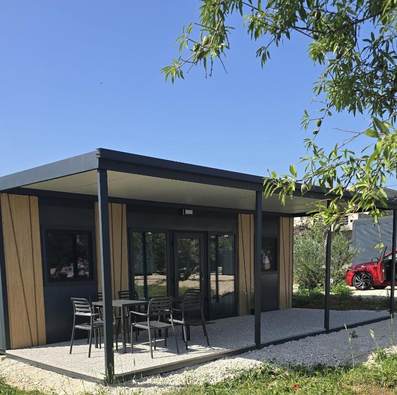 a building with a table and chairs in front of it at Vila Mia 3, camp Limoni in Sukošan