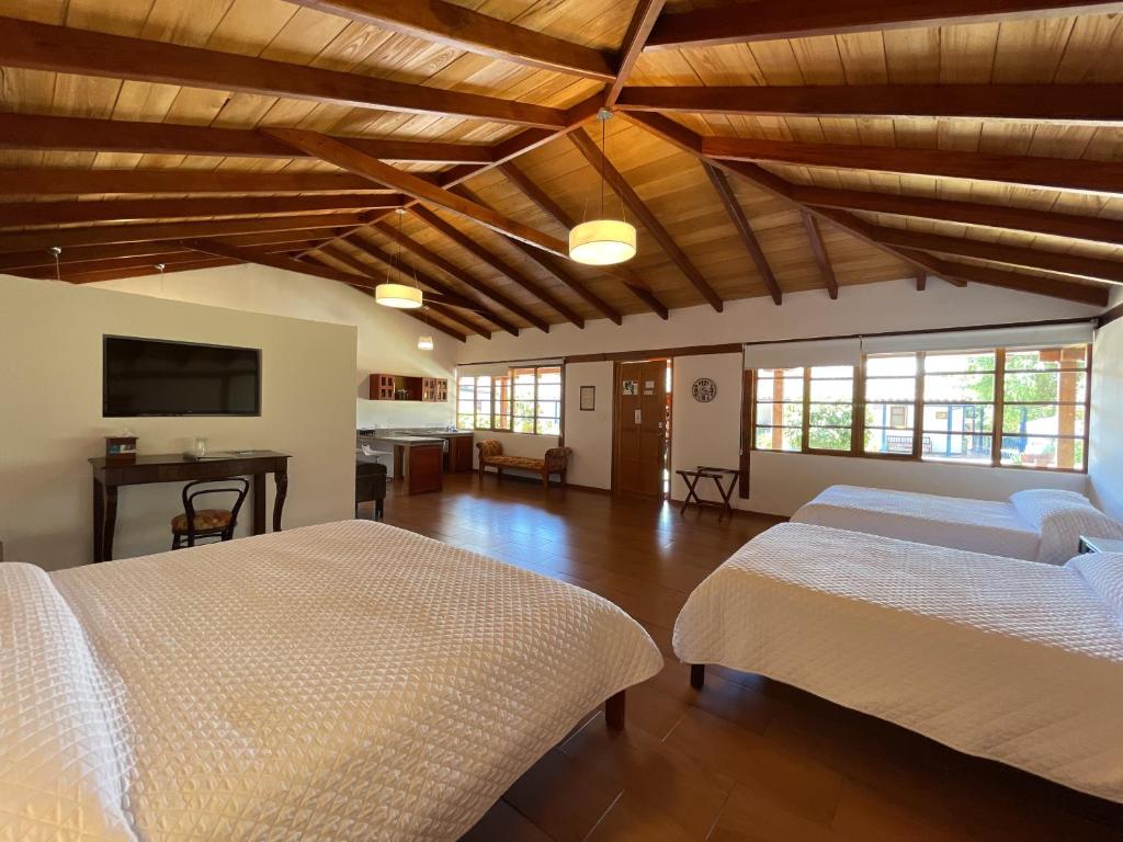 a large room with two beds and a flat screen tv at Hacienda Hosteria Chorlavi in Ibarra