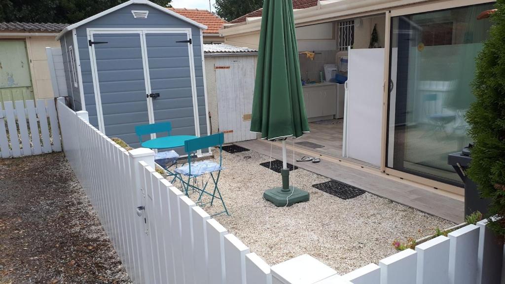 un parasol et une table et une chaise et une table et une clôture dans l'établissement Location vacances, à La Bernerie-en-Retz