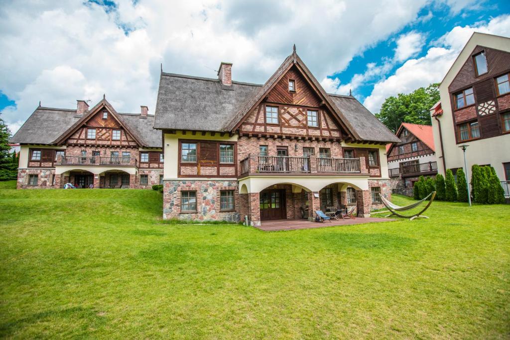 a large house with a large yard with green grass at Hotel Aubrecht Country Spa Resort in Przechlewo