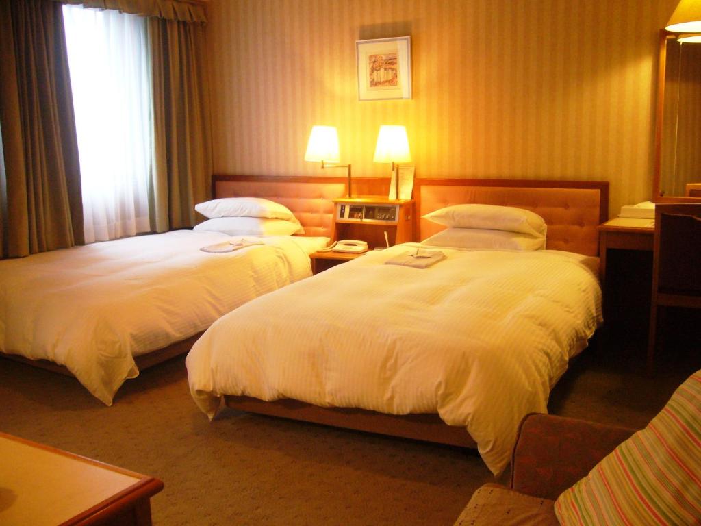 a hotel room with two beds and a window at Hotel Crown Hills Sendai Aobadori in Sendai