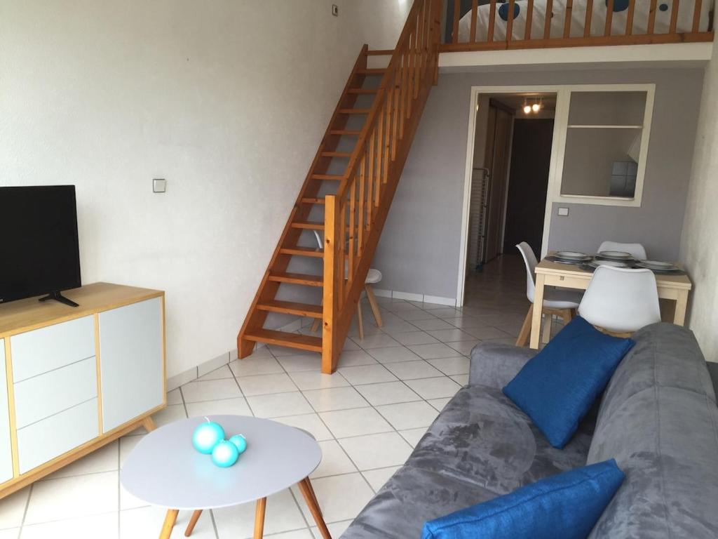 un salon avec un canapé et un escalier dans l'établissement Appart à 2 pas de la grande plage, à Les Sables-dʼOlonne