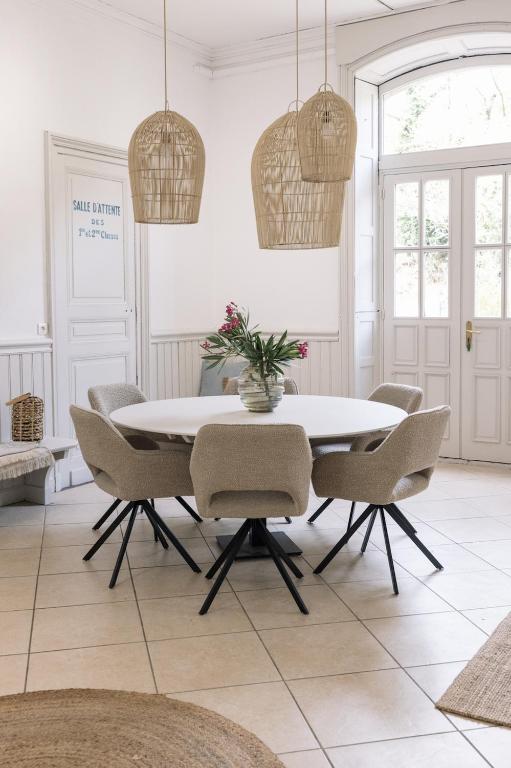 une salle à manger avec une table et des chaises blanches dans l'établissement LA GARE DE L'ART - Gästehaus im ehemaligen Bahnhof, à Rouairoux