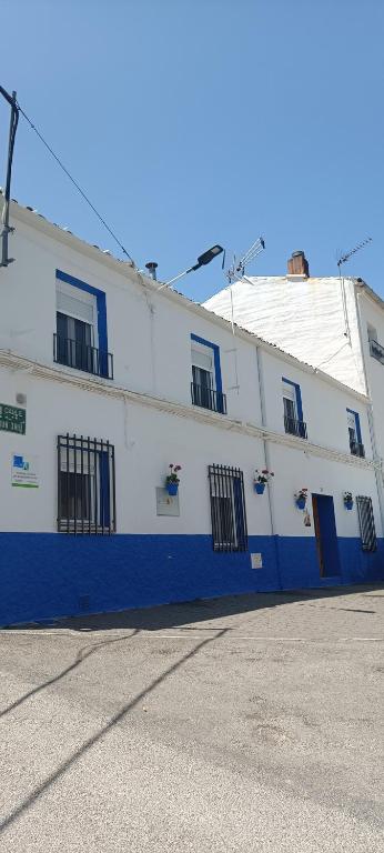 a white building with blue doors and windows at Xenia Alojamientos in Santiago de la Espada