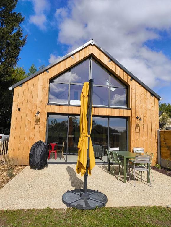 un parapluie jaune assis devant un bâtiment dans l'établissement LES PATICHERES - L'Atelier avec accès à la piscine, à Biville-la-Baignarde