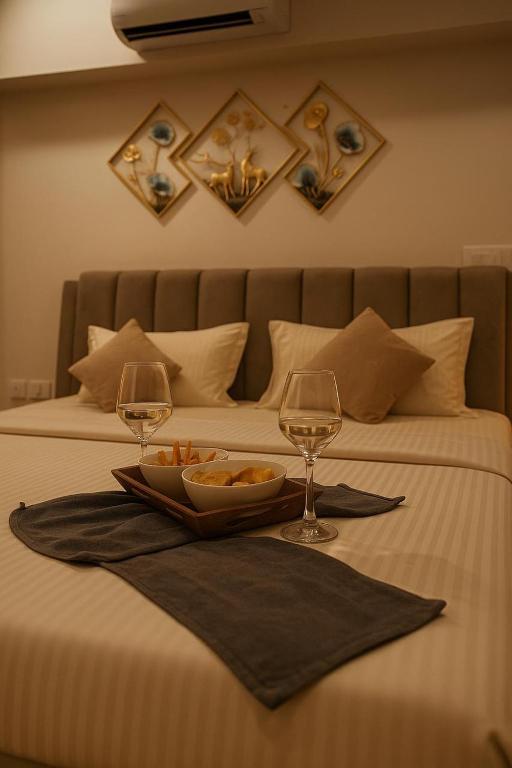 a tray of food and two wine glasses on a bed at Viento in Dehu Road