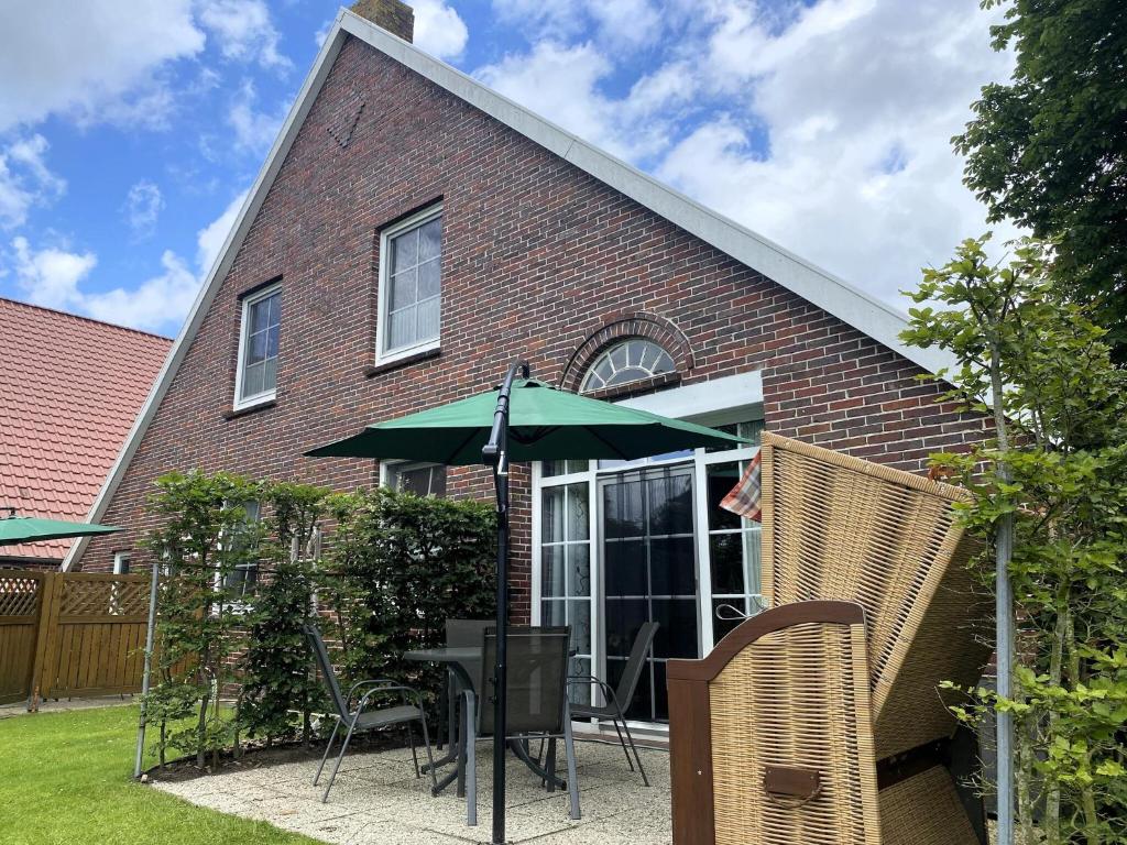 a patio with a table with an umbrella and chairs at Reihenhäuser in Strackholt in Strackholt